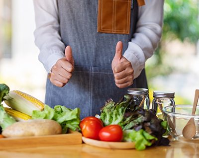 Closeup image of a female chef making and showing thumbs up hand